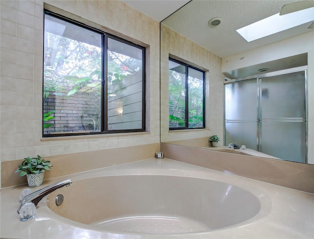 bathroom with tile walls, plus walk in shower, a textured ceiling, and a skylight