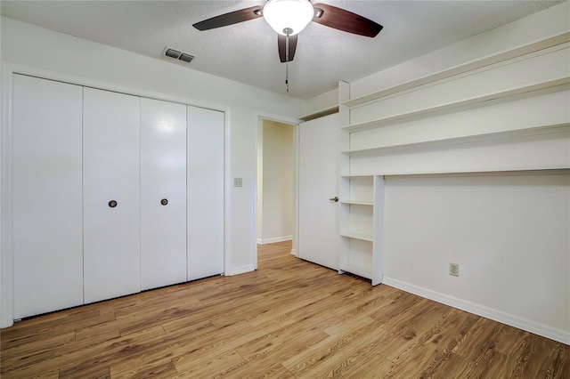 unfurnished bedroom featuring light hardwood / wood-style floors, a closet, ceiling fan, and a textured ceiling