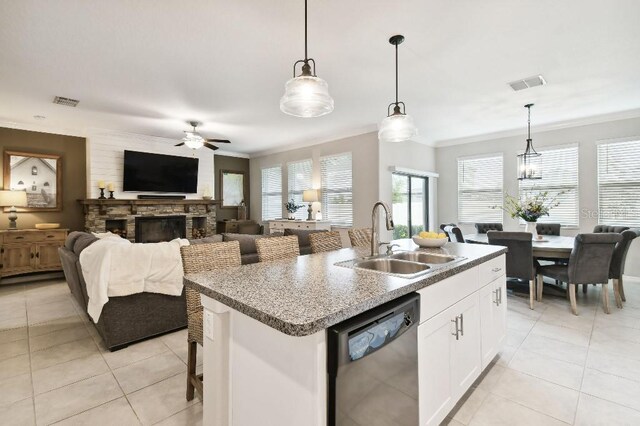 kitchen featuring hanging light fixtures, a center island with sink, dishwashing machine, and white cabinets