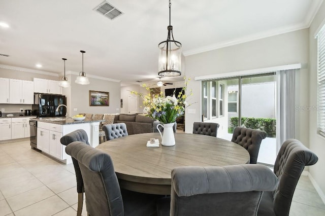 tiled dining space featuring sink, ceiling fan, and crown molding