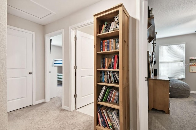 hallway featuring light colored carpet and a textured ceiling