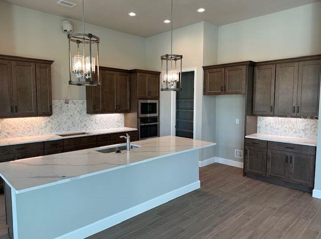 kitchen with pendant lighting, sink, light stone counters, and black appliances