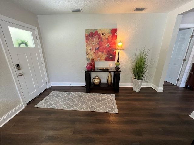 foyer entrance with dark hardwood / wood-style floors and a textured ceiling