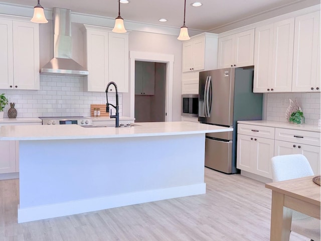 kitchen featuring hanging light fixtures, white cabinets, wall chimney exhaust hood, and stainless steel appliances