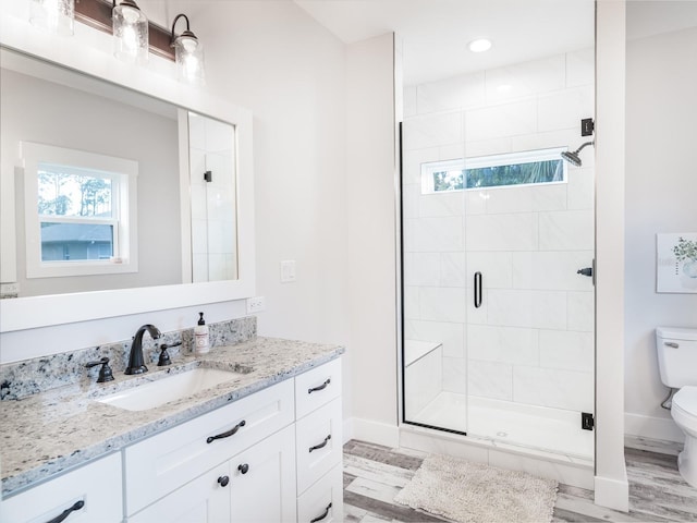 bathroom with toilet, wood-type flooring, an enclosed shower, and vanity