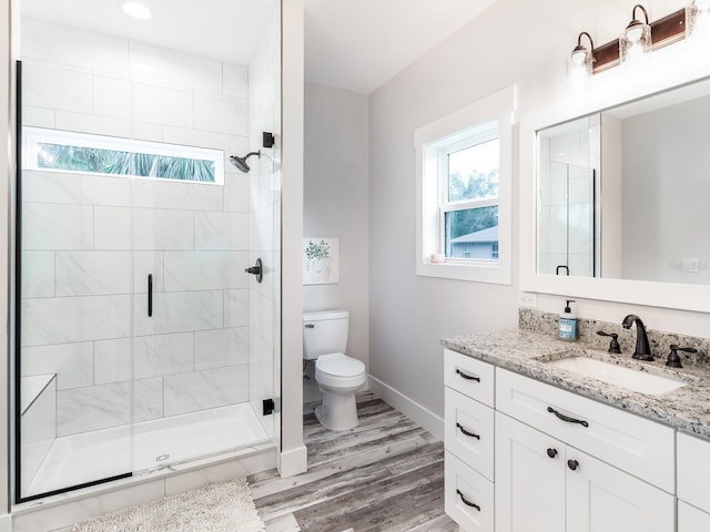 bathroom featuring toilet, a shower with shower door, hardwood / wood-style flooring, and vanity