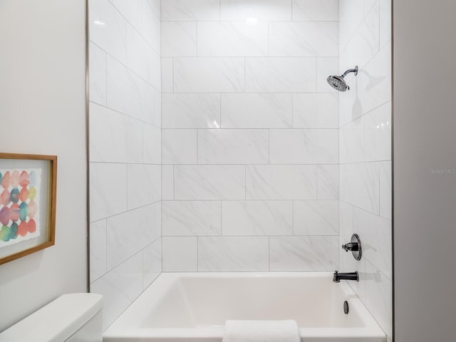 bathroom featuring toilet and tiled shower / bath