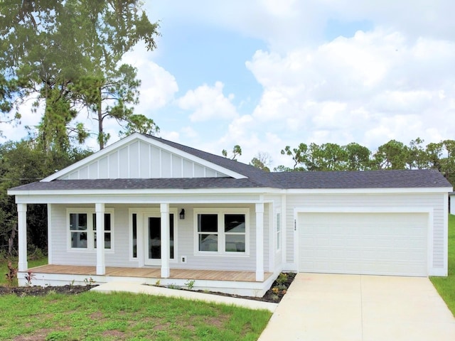 view of front of property featuring a front yard, a porch, and a garage