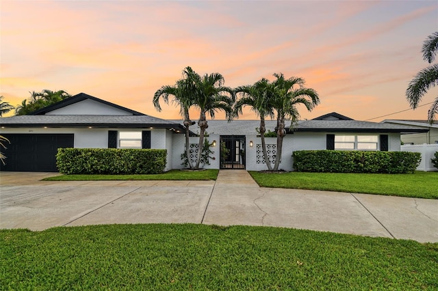 single story home with a garage and a lawn