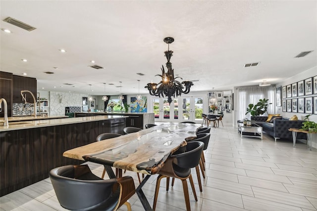 dining space featuring french doors, an inviting chandelier, and sink