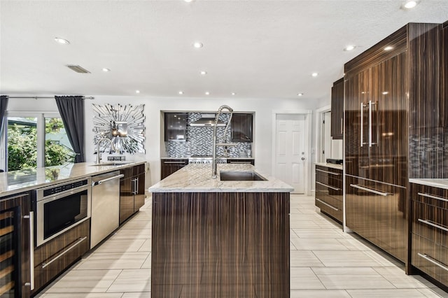 kitchen featuring wine cooler, stainless steel appliances, sink, and a center island with sink