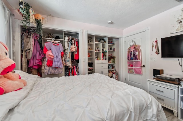 bedroom with a textured ceiling and two closets