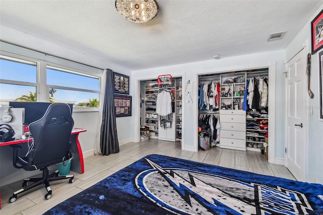 bedroom with multiple closets and a textured ceiling