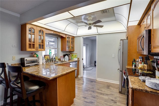 kitchen with dark stone counters, sink, ceiling fan, appliances with stainless steel finishes, and kitchen peninsula