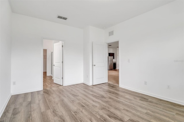 unfurnished bedroom featuring stainless steel refrigerator and light hardwood / wood-style floors