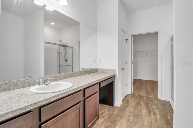 bathroom with walk in shower, vanity, and hardwood / wood-style flooring