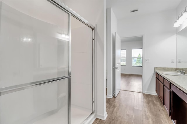 bathroom with walk in shower, vanity, and hardwood / wood-style flooring