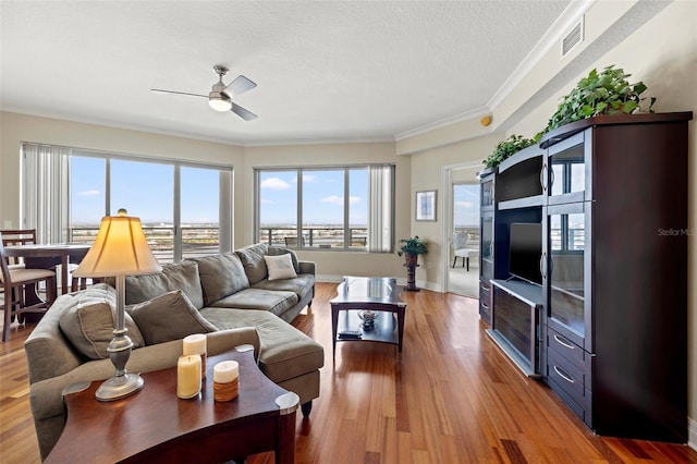 living room with crown molding, light hardwood / wood-style flooring, ceiling fan, and a textured ceiling