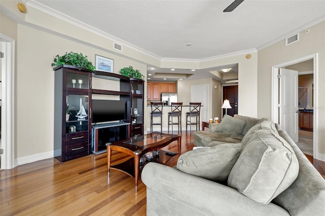 living room with ceiling fan, crown molding, and light hardwood / wood-style flooring