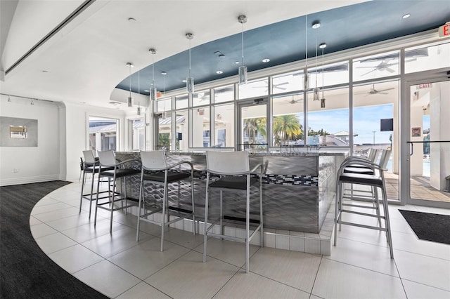 bar featuring tile patterned flooring, decorative light fixtures, ceiling fan, and a healthy amount of sunlight