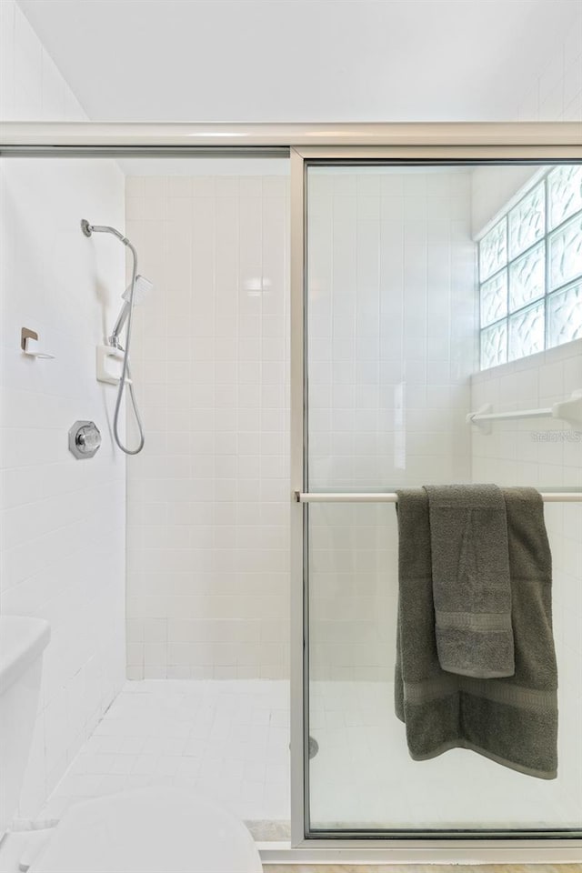 bathroom featuring toilet and a shower with door