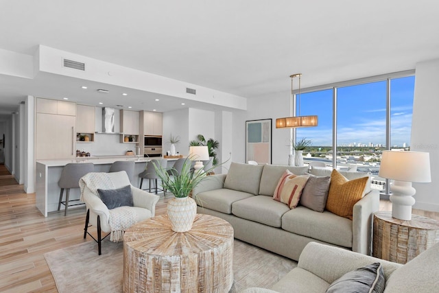 living room with expansive windows and light hardwood / wood-style floors