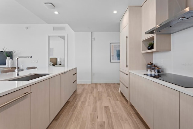 kitchen featuring sink, wall chimney range hood, black electric stovetop, and light hardwood / wood-style flooring