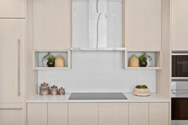 interior space with stainless steel appliances, wall chimney exhaust hood, and cream cabinets