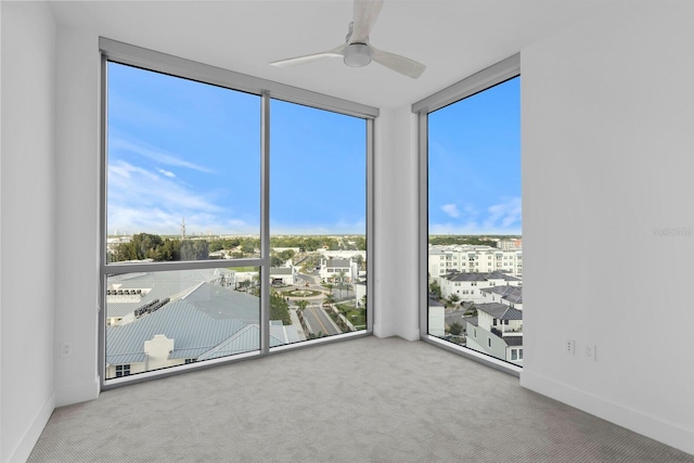 unfurnished room featuring a wall of windows, ceiling fan, and carpet