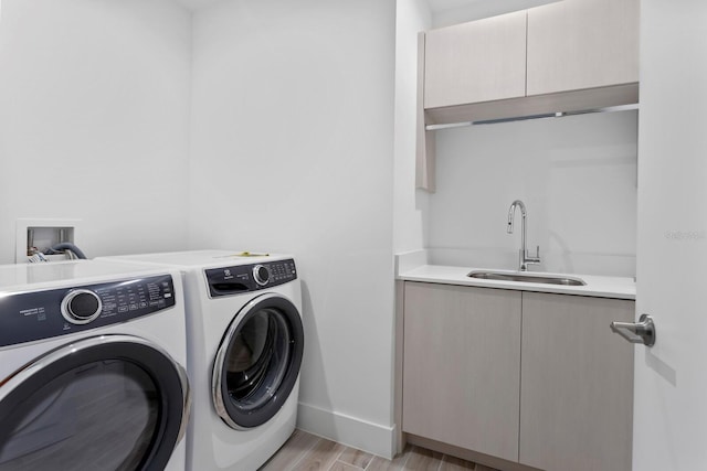 laundry room with sink, washing machine and dryer, and cabinets