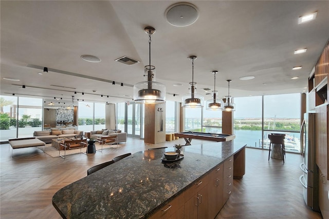 kitchen with pendant lighting, light parquet flooring, pool table, dark stone counters, and a large island