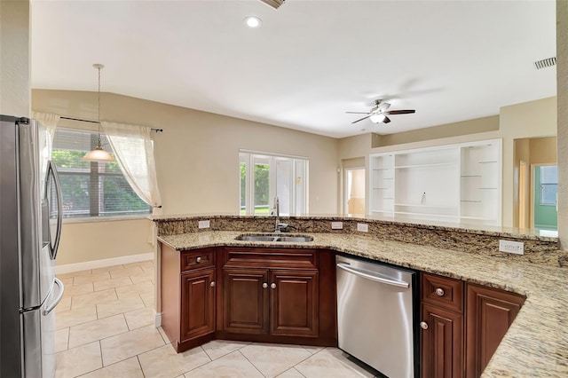 kitchen featuring light stone countertops, appliances with stainless steel finishes, pendant lighting, and sink