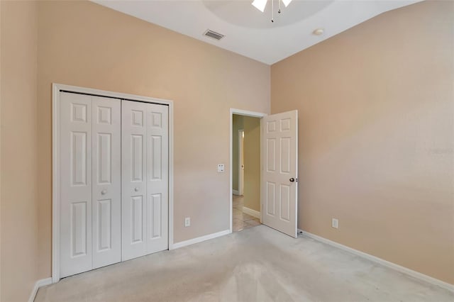 unfurnished bedroom with ceiling fan, a closet, and light carpet