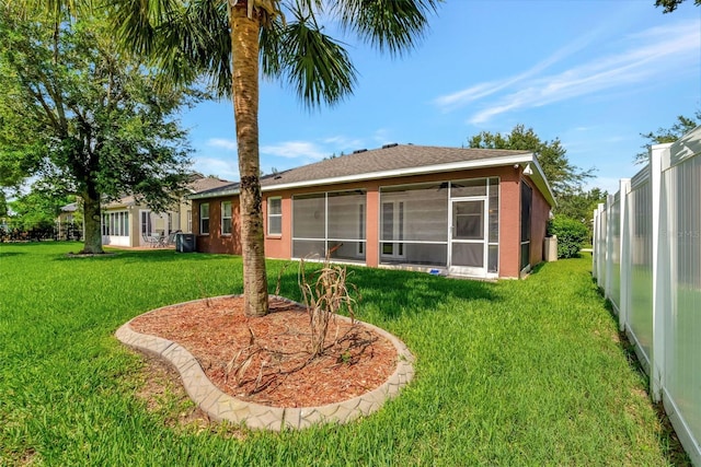 back of property featuring a sunroom and a yard