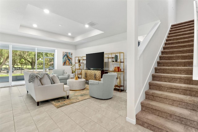 living room featuring a raised ceiling and light tile patterned floors