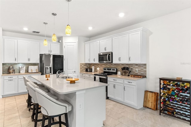 kitchen with white cabinetry, appliances with stainless steel finishes, sink, and an island with sink