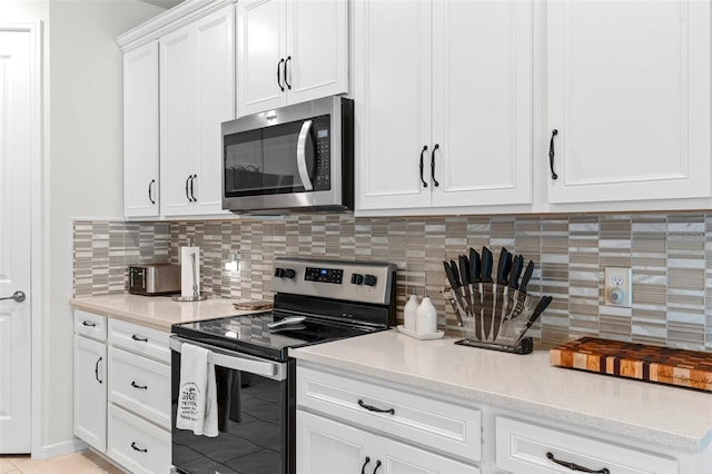 kitchen featuring stainless steel appliances, decorative backsplash, and white cabinets