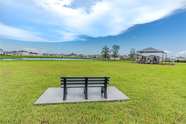 view of home's community with a playground, a water view, and a lawn