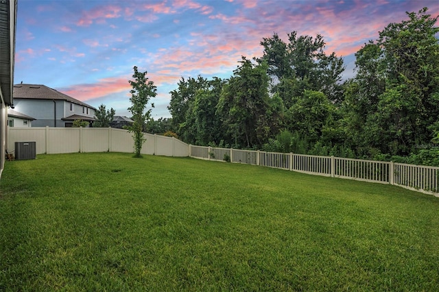 yard at dusk featuring central AC