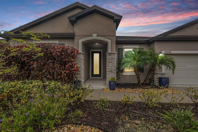 exterior entry at dusk featuring a garage