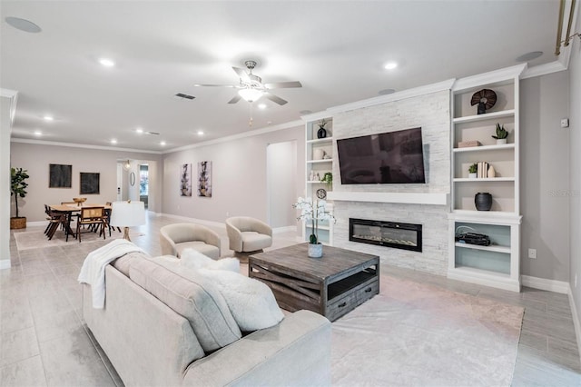 living room with ceiling fan, built in shelves, ornamental molding, and a fireplace