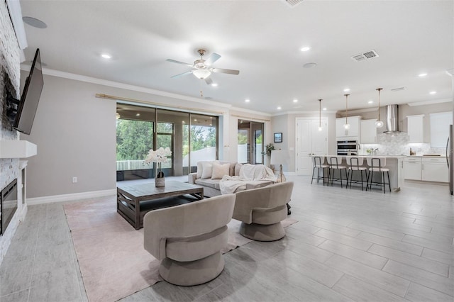 living room featuring ceiling fan, a fireplace, and ornamental molding