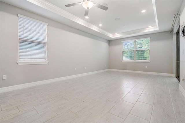 empty room featuring ceiling fan, ornamental molding, and a raised ceiling