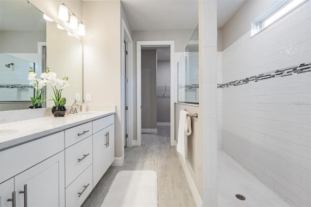 bathroom with a tile shower and vanity