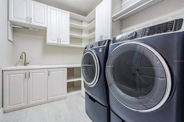 laundry area with cabinets, washer and dryer, and sink