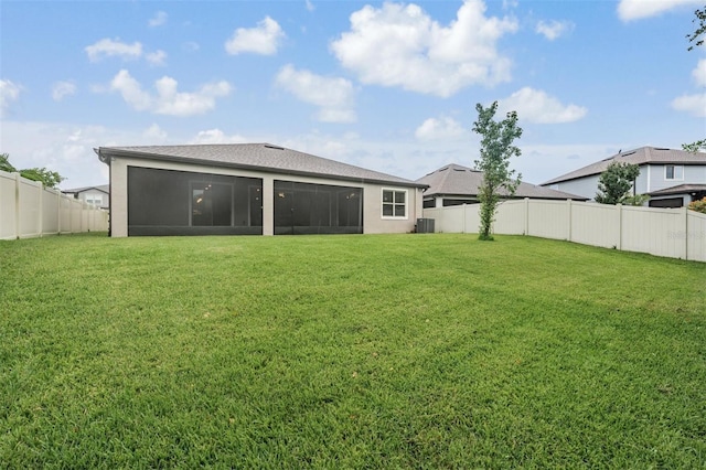 rear view of property with a sunroom, cooling unit, and a lawn