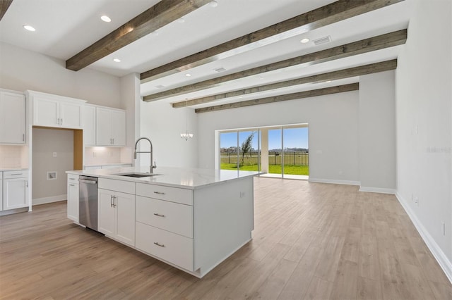 kitchen featuring stainless steel dishwasher, beam ceiling, a sink, light countertops, and light wood-style flooring