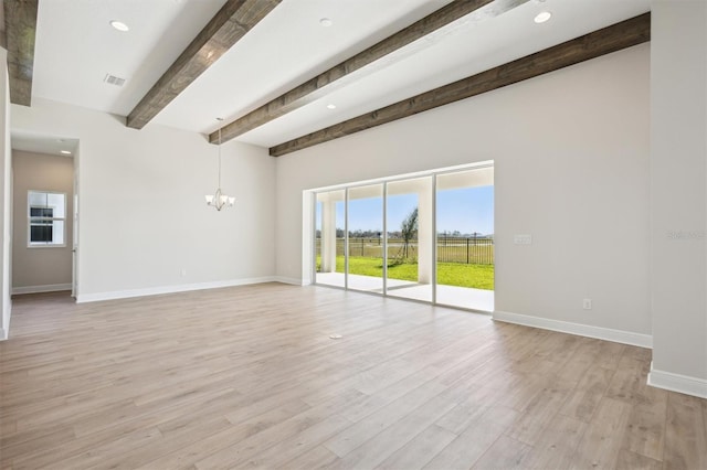 empty room with beamed ceiling, an inviting chandelier, plenty of natural light, and baseboards
