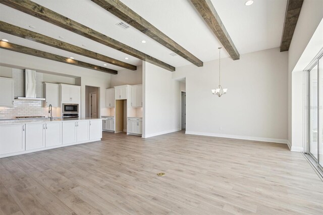 unfurnished living room with baseboards, light wood-style flooring, and a notable chandelier