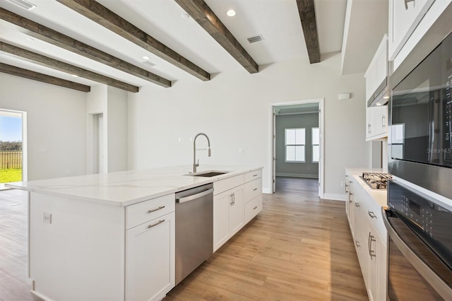 kitchen with stainless steel appliances, a center island with sink, sink, white cabinets, and light hardwood / wood-style floors